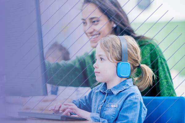Teacher and a student wearing headphones working on a computer together